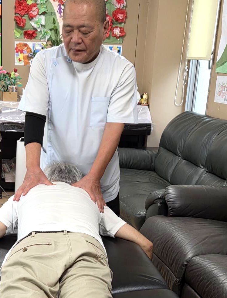 施術者がご利用者の背中に両手を当て、ていねいに施術しているようす。
